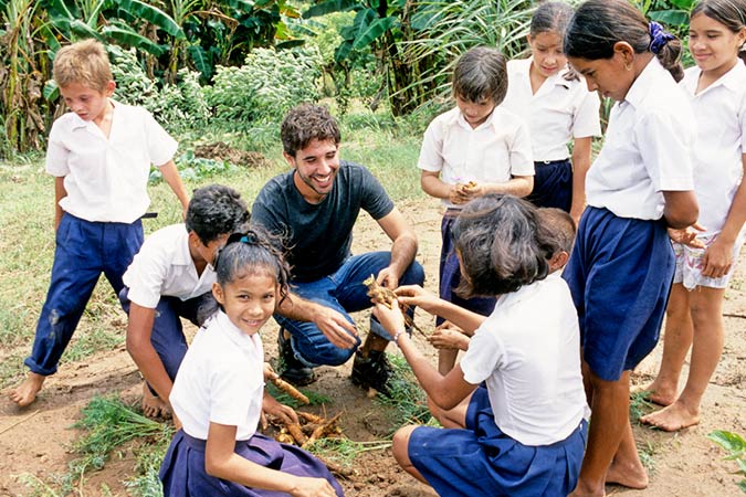 peace corps member with young class outside looking at vegetation
