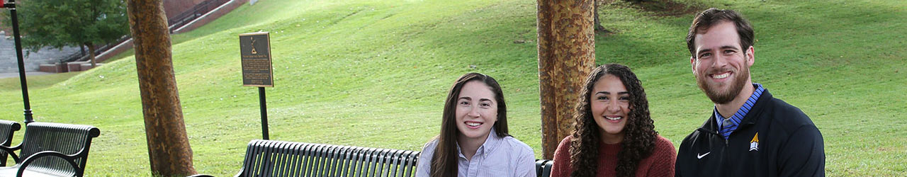 three students enjoying the afternoon on campus