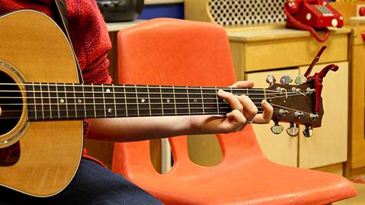 pick and bow student holding a guitar