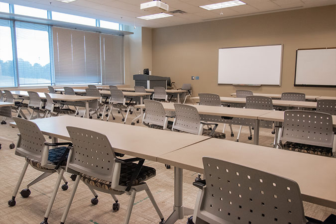 view of thelong tables and chairs arranged in a classroom