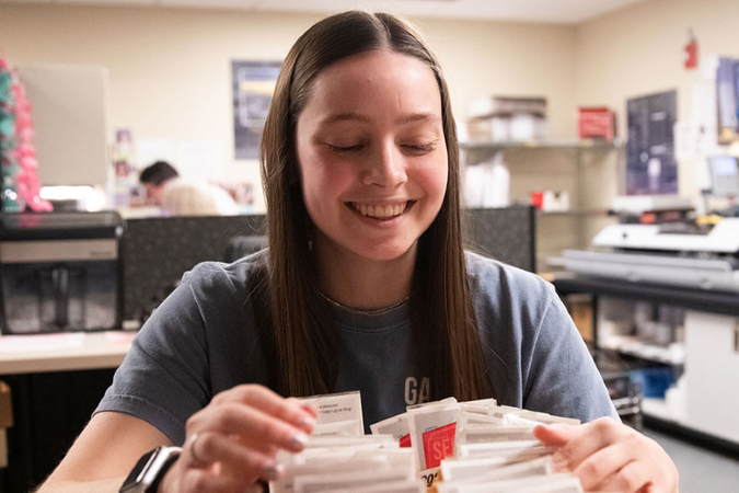 smiling student sorting mail 