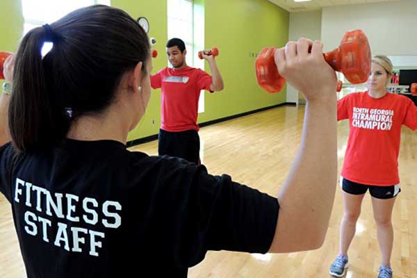 fitness instructor leading class with dumbbells