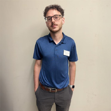 Jonathan standing with hands in pockets, at work