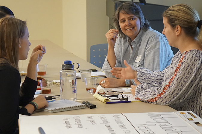 Faculty sitting around table talking at HIPs academy.