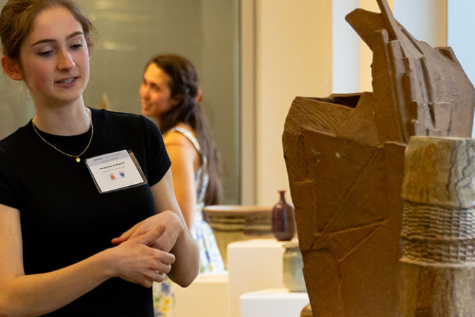student standing next to an abstract sculpture 