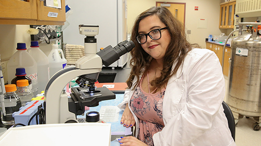 Jessica Nix, an S-STEM Scholar, looking into a microscope