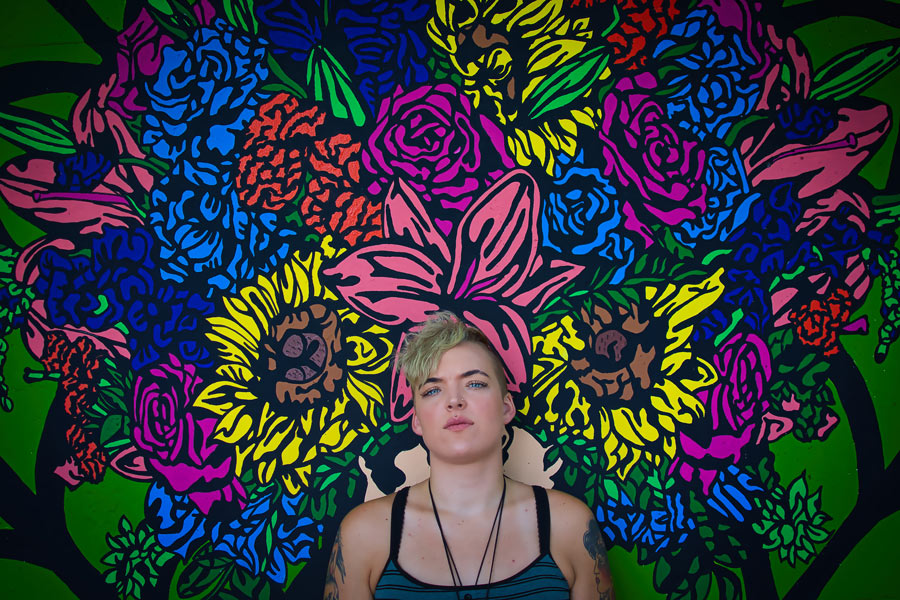 portrait of person against vibrantly colored artwork of flowers in background