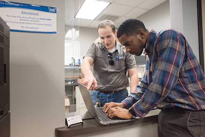 student worker helping another student with his computer