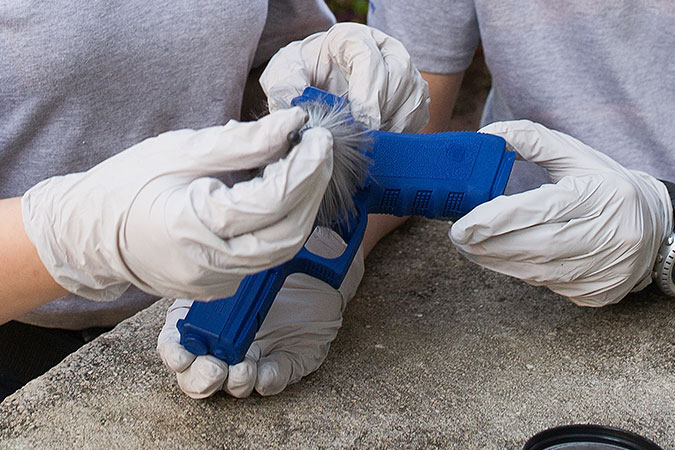 students dusting a gun for fingerprints