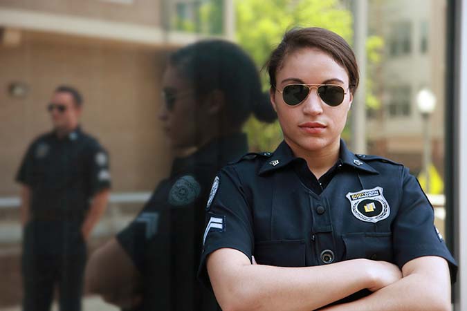 Policewoman leaning against reflective wall.