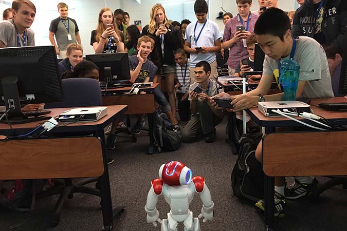students gather around a small robot 