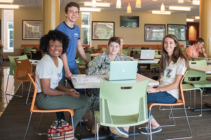 students seated at a table around a laptop