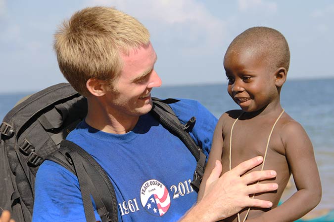 peace corps member holding up young child