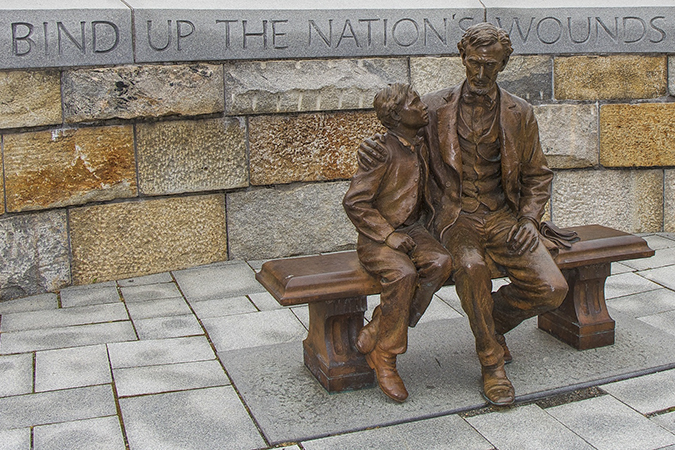 Abraham Lincoln sitting with a boy, text behind,To Bind Up the Nations Wounds