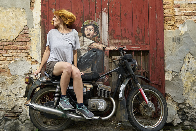 Woman on motorcycle in front of a painted door.