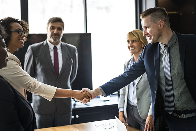 People meeting and two shaking hands in agreement.