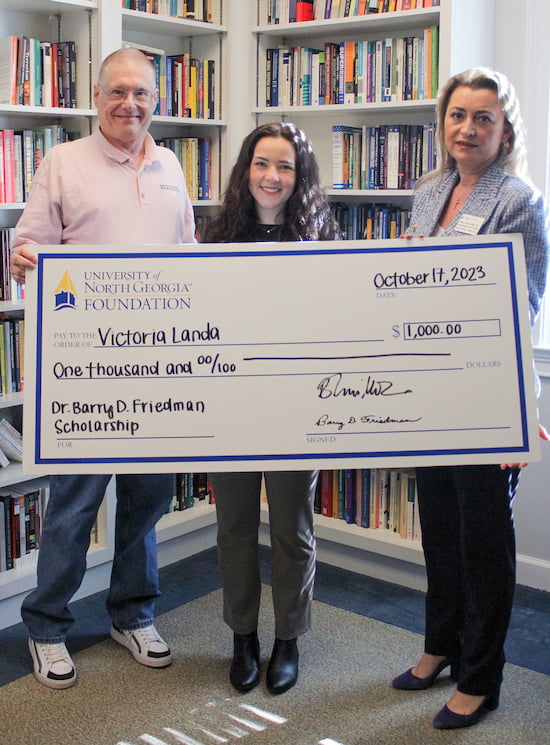 Doctors Friedman and Viman-Miller stand beside Victoria Landa holding an oversized scholarship check for one grand.